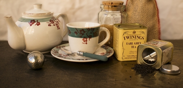 Teapot, steeping ball, teacup, and tin of Twinings Earl Grey teabags